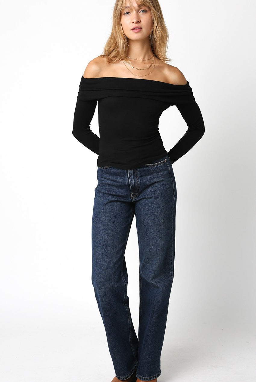 Zena Black Off-Shoulder Long Sleeve Top with a ribbed texture and fold-over neckline paired with dark wash denim jeans.