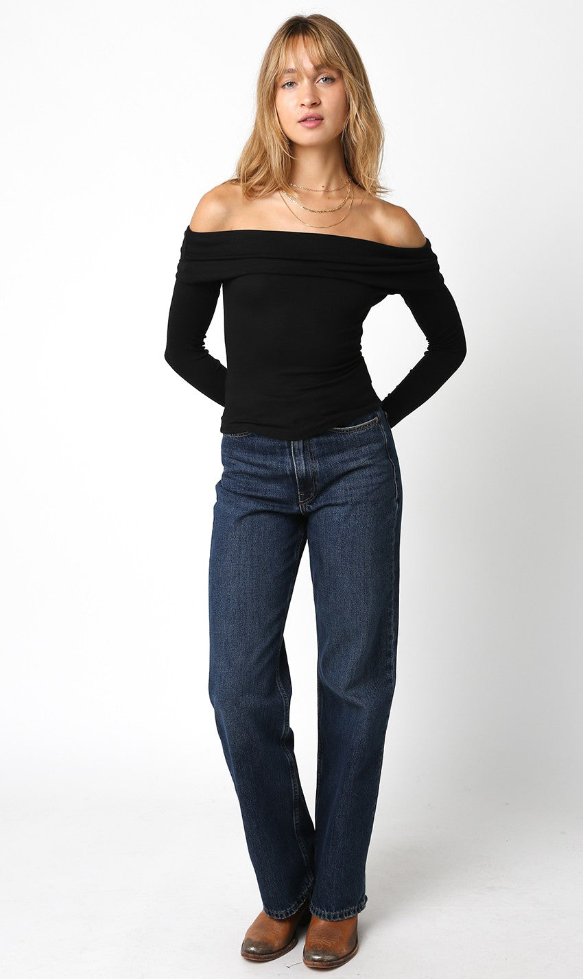 Zena Black Off-Shoulder Long Sleeve Top with a ribbed texture and fold-over neckline paired with dark wash denim jeans.