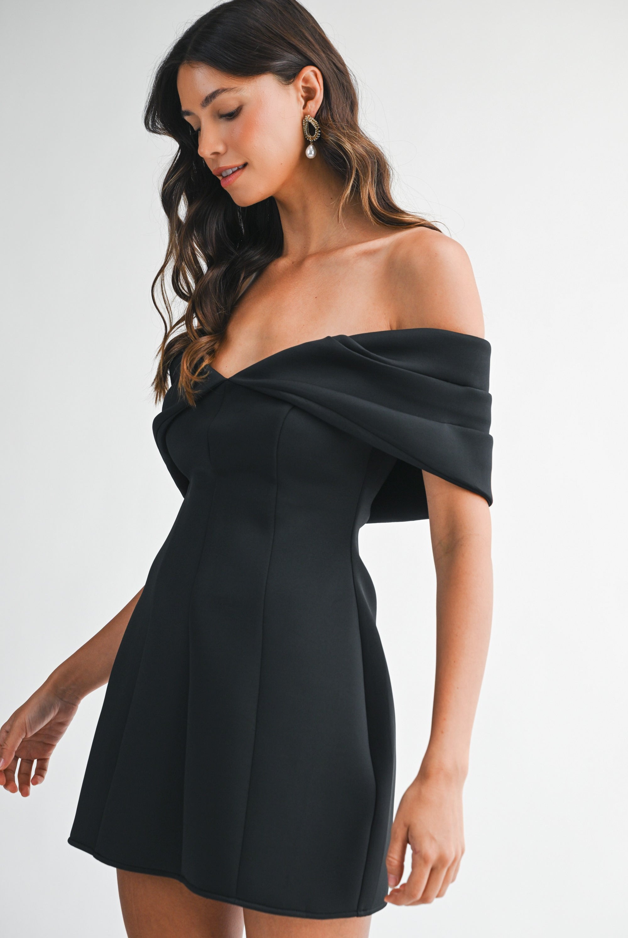 Side view of the black mini dress showing the fitted bodice off-the-shoulder nekline