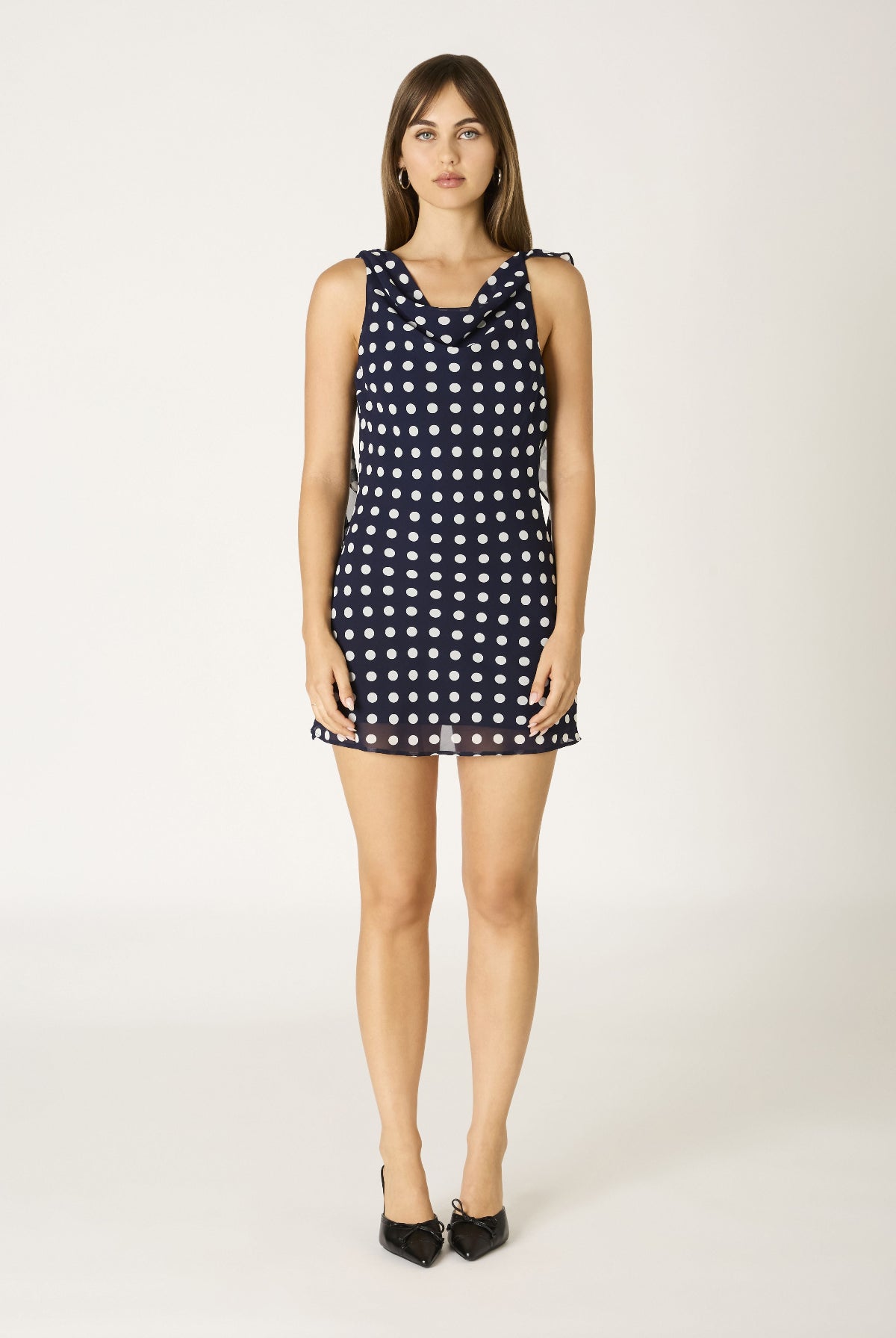Full body shot of a cute sleeveless mini dress in navy blue and white polka dots