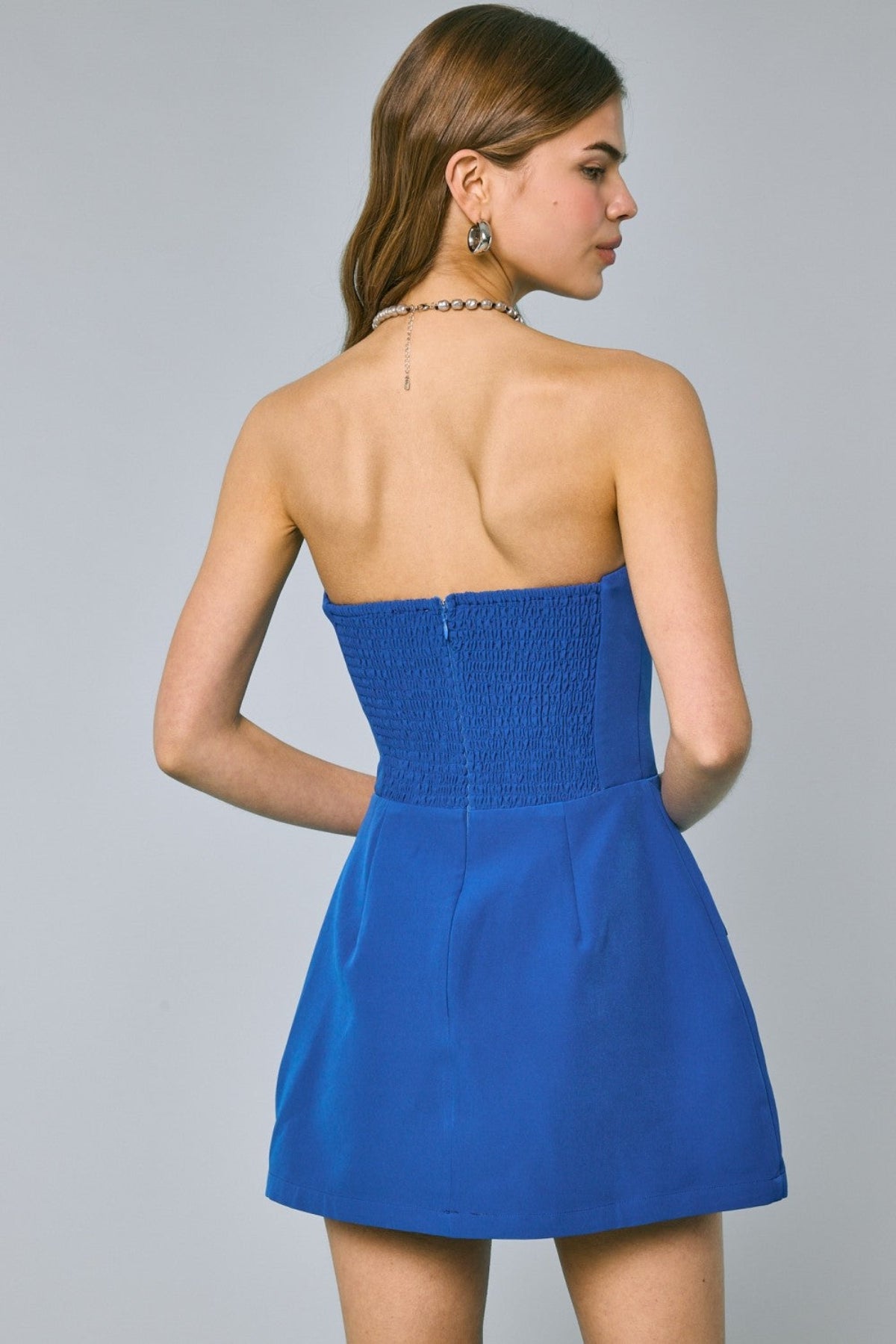 Back view of royal blue strapless romper showing the stretchy smocked panel for a secure fit.