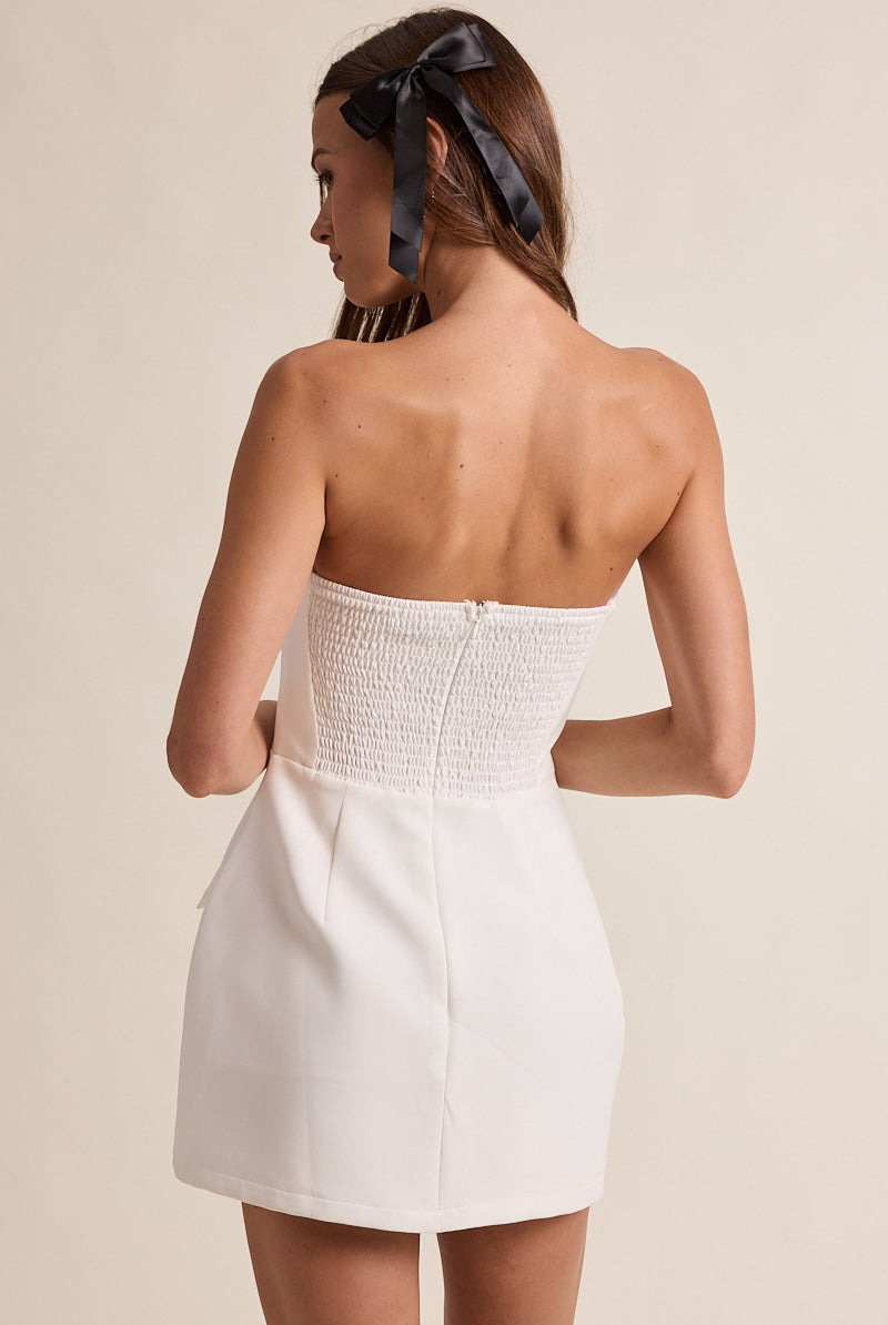 Back of white strapless romper featuring a stretchy smocked panel and hidden zipper for a secure fit