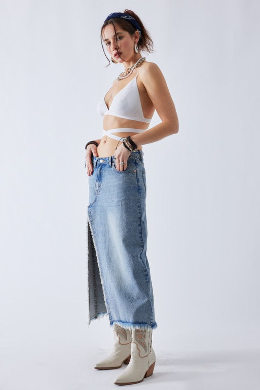 Frayed raw hem and side slit detail on a light wash denim maxi skirt.