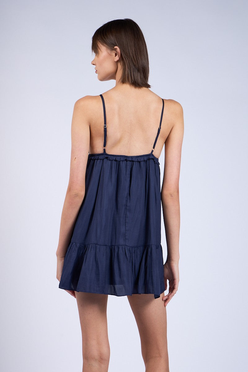 Back view navy blue mini dress for date night, styled as a flowy babydoll dress with adjustable straps.