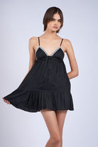 Model wearing the Annie Black Babydoll Dress showing the ribbon lace trim along the neckline and the airy tiered hemline.