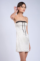 Detail of ivory lace-trim neckline and dainty ribbon on polka dot satin