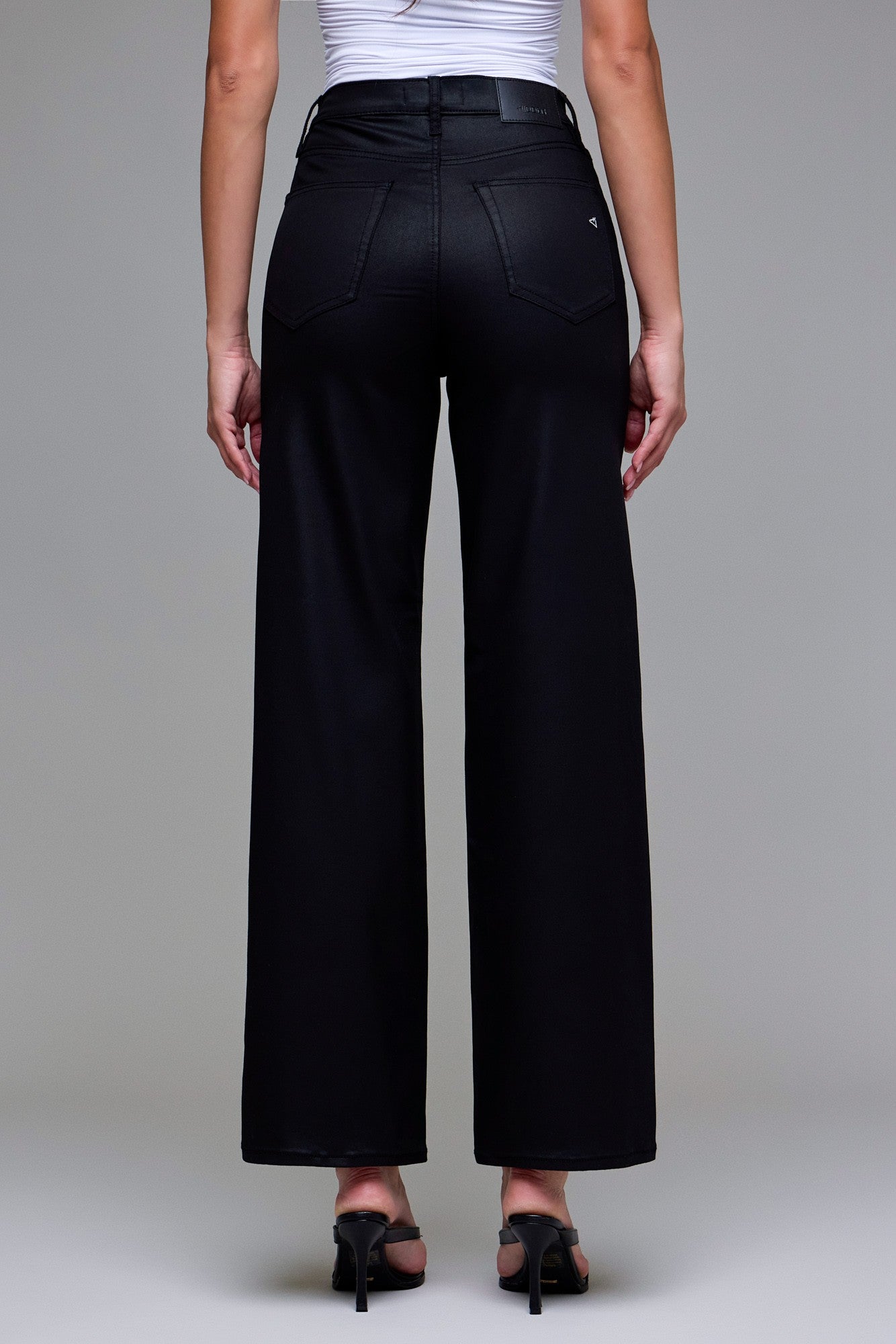 Model wearing Abby black coated dad jeans styled with heels for an edgy night-out look.