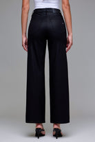 Model wearing Abby black coated dad jeans styled with heels for an edgy night-out look.