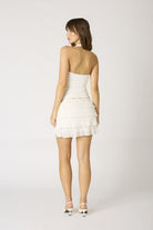 Moeel view of the Agathe white halter top styled with a white lace mini dress