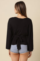 Black dolman sleeve top featuring adjustable back tie waist