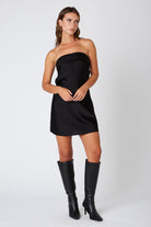 Model wearing a black satin strapless mini dress with heels for a celebration look
