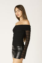 Vacation outfit featuring a black lace off-the-shoulder top styled for an evening out