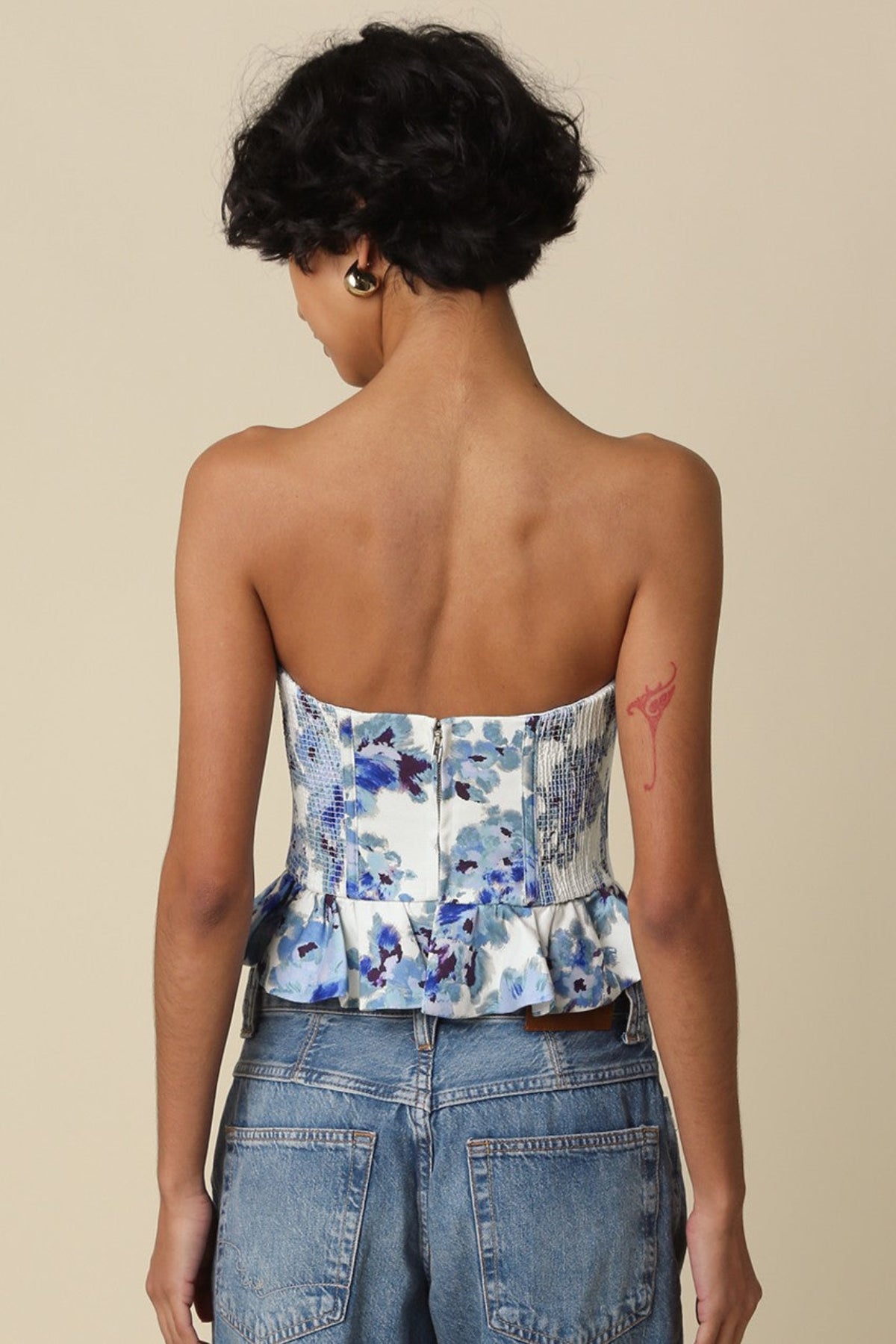 Back view of the Dani floral top showing the smocked side panels and center back zipper