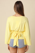 Yellow dolman sleeve top featuring adjustable back tie waist