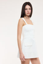 Women's white utility denim mini dress with wide straps.