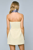 Back view of yellow strapless mini dress showing smocked panel and hidden zipper closure.
