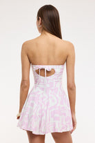 Chic coastal vacation outfit featuring a pink and white romper dress back view