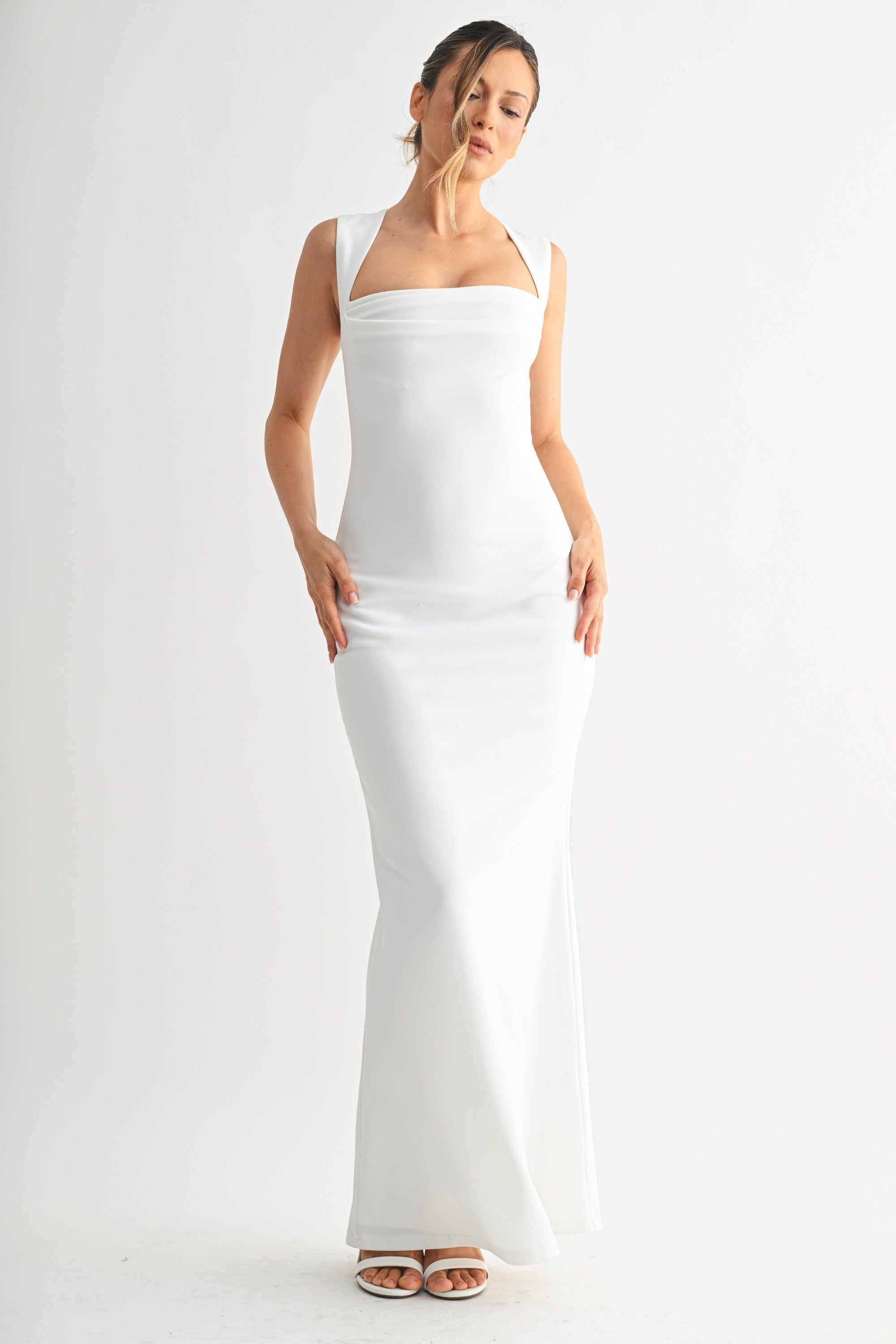 Full length view of a woman wearing a sleek white sleeveless gown with a flared hem
