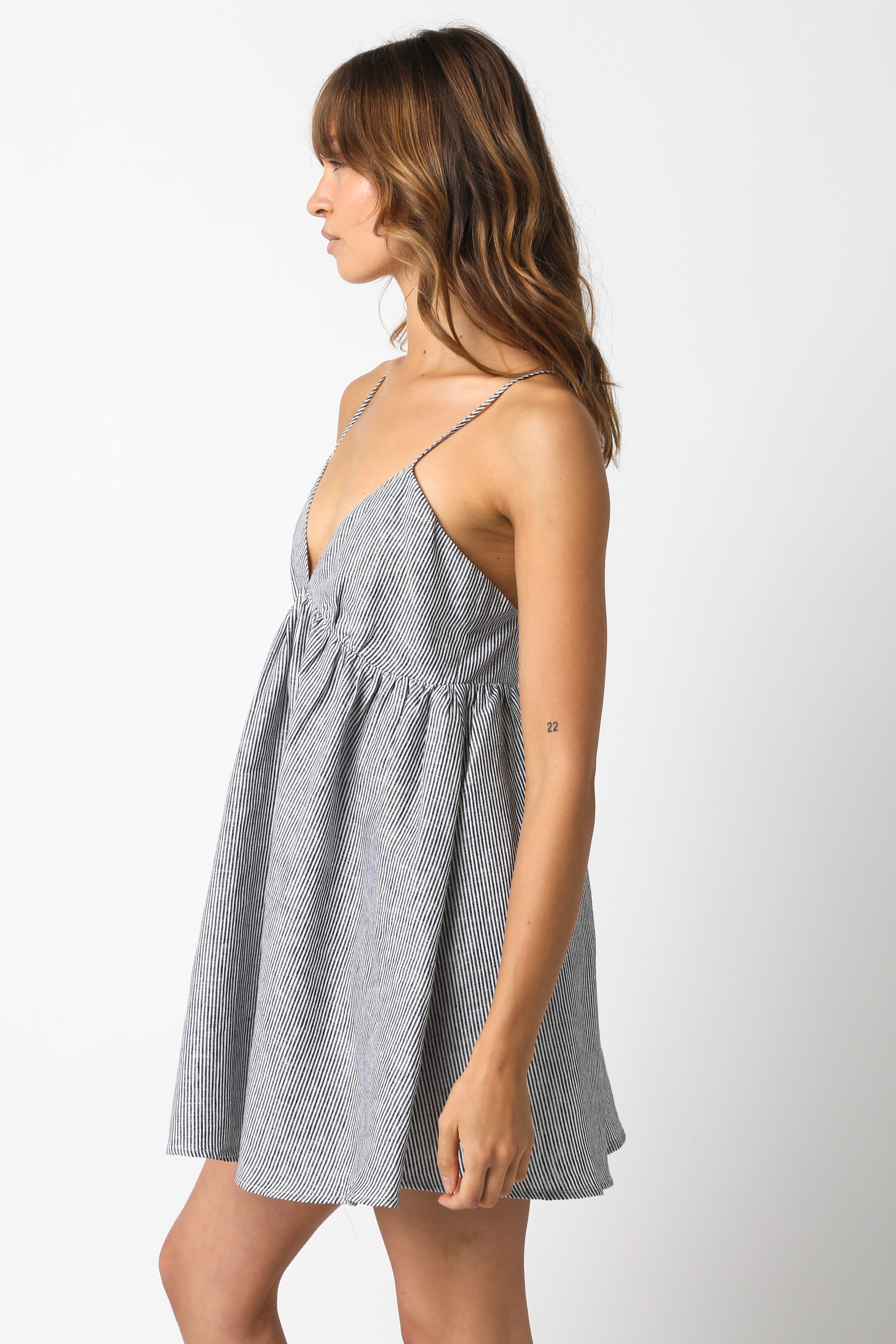 Side view of black striped linen mini dress showing the babydoll silhouette