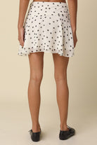 Back view of the flirty flared silhouette and ruffle hemline of the Eleni white polka dot skirt