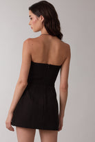 Back view of black strapless mini dress showing smocked panel and hidden zipper closure.